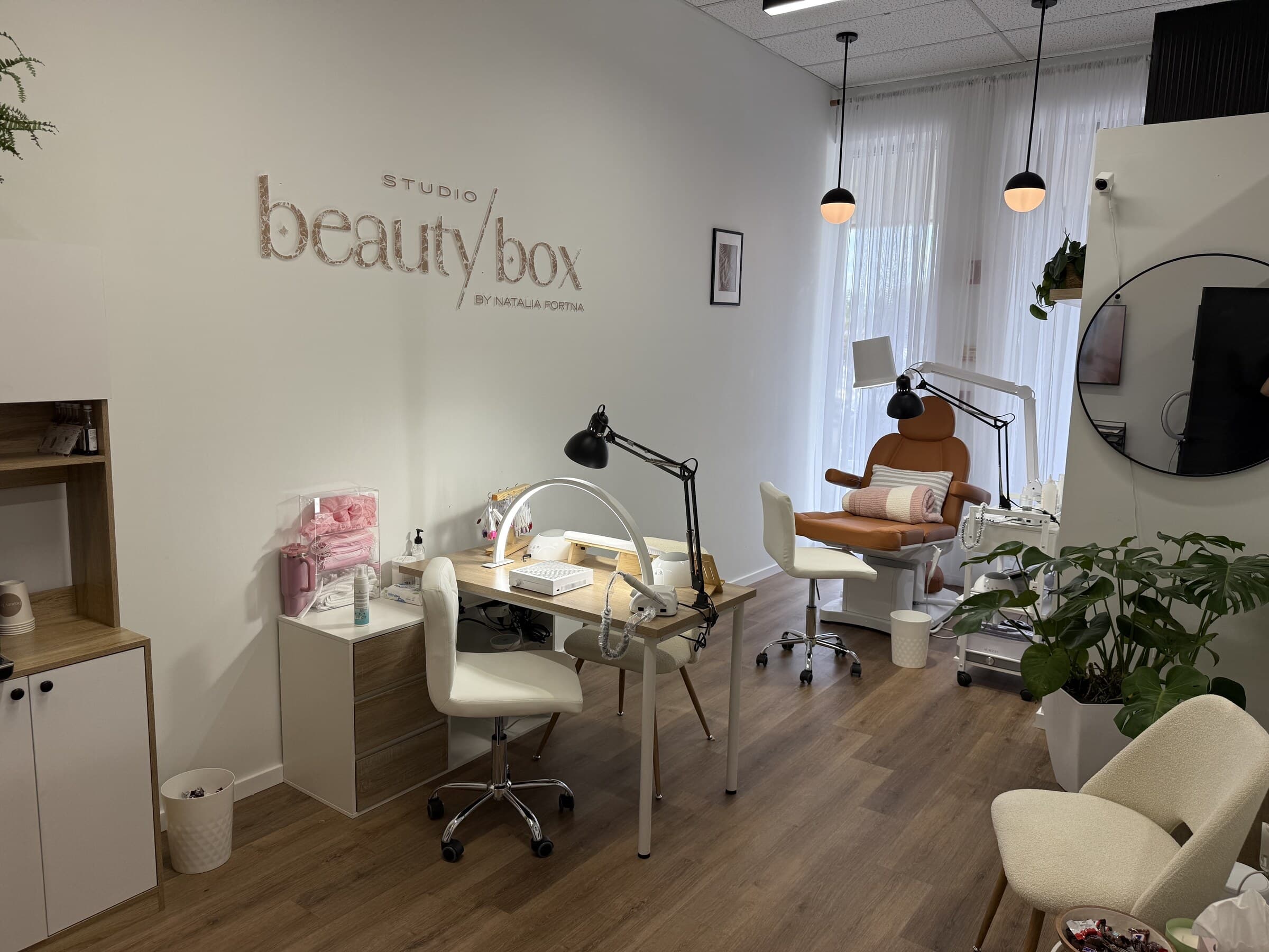 Inside Studio Beauty Box in Orlando: a single manicure desk with a lamp, a pedicure chair by the window and the studio sign on the wall