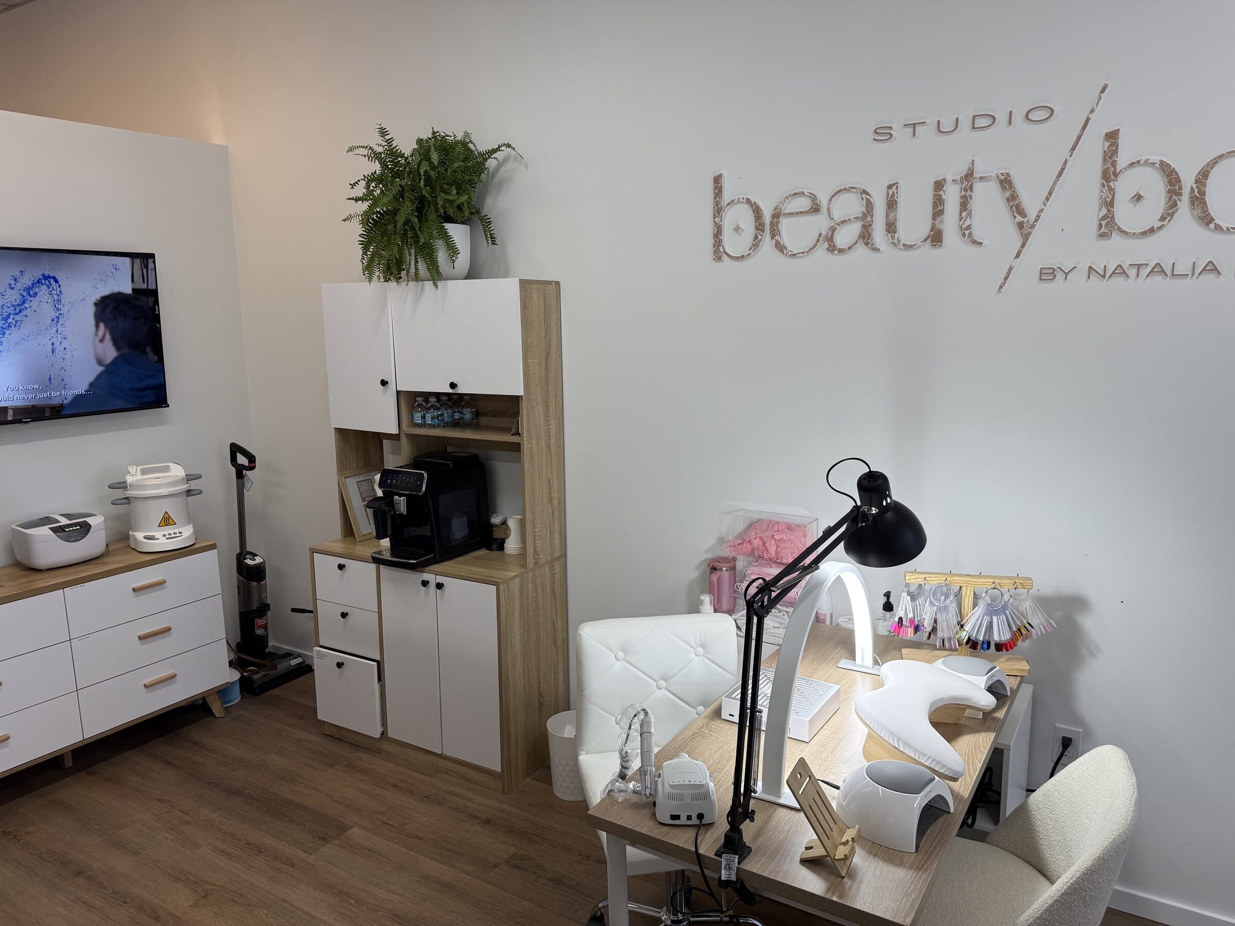 The working corner of Studio Beauty Box: sterilisation equipment on the cabinet, colour samples above the desk, coffee for guests